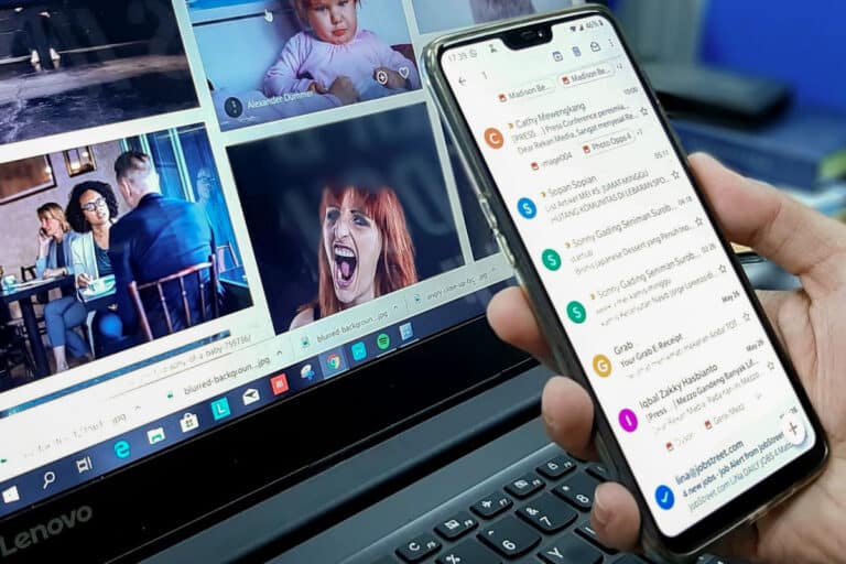 Smartphone montrant des e-mails devant un ordinateur portable.