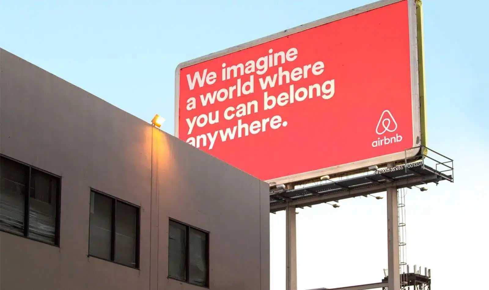 Panneau publicitaire rouge avec slogan Airbnb.