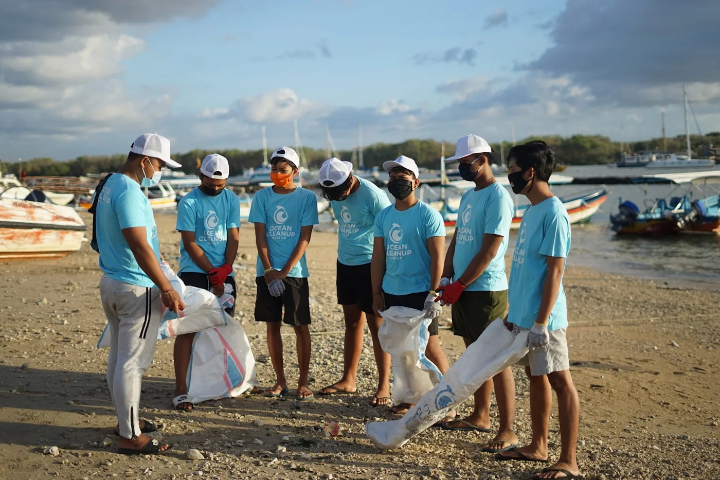 Équipe de bénévoles en t-shirts assortis ramassant des déchets sur une plage