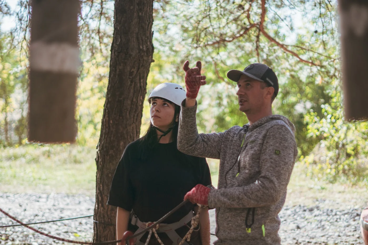 Instructeur guidant une participante casquée lors d'une session d'accrobranche
